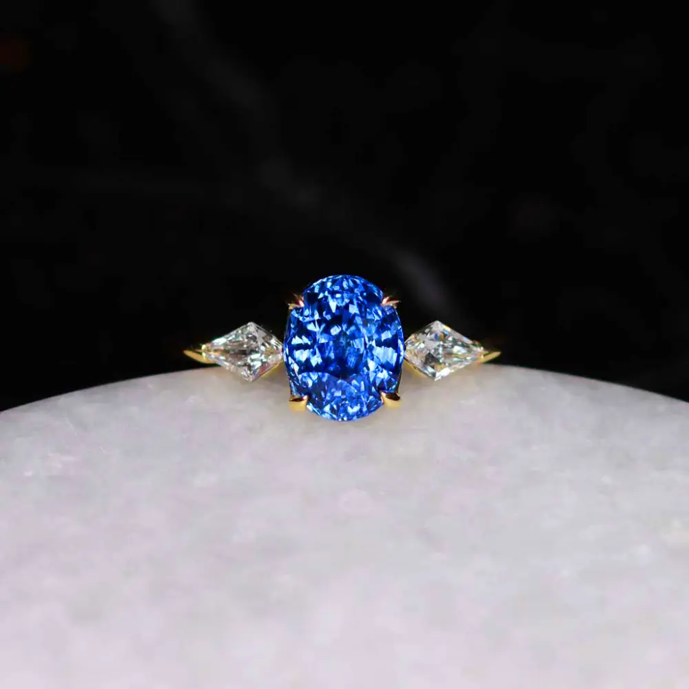 An oval Ceylon blue sapphire ring flanked by two diamonds